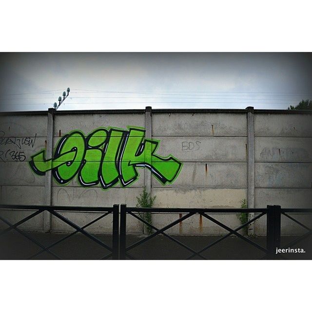 transfer print, graffiti, auto post production filter, built structure, architecture, text, wall - building feature, western script, art, wall, creativity, building exterior, low angle view, sky, green color, art and craft, outdoors, communication, day, multi colored