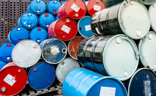 Old chemical barrels on wooden pallet. blue and red oil drum. steel and plastic oil tank. 