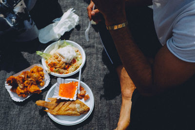 Low section of man eating food on floor