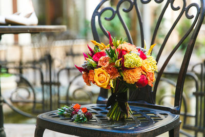 Bouquet of orange roses and alstromeria on a black metal forged chair