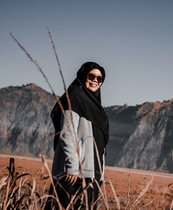 Low angle view of smiling woman standing on field against sky