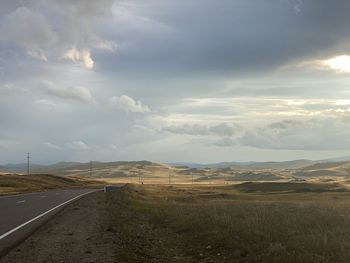 Scenic view of road amidst field against sky