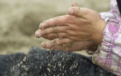Cropped hands of child spilling sand
