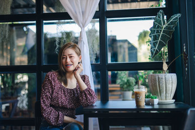 Portrait of a smiling young woman sitting on table