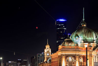 Illuminated flinders street station, buildings in city and super moon at night