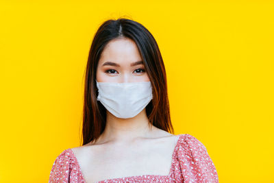 Portrait of beautiful young woman against yellow background