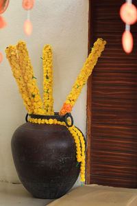 Close-up of yellow lamp on table against wall