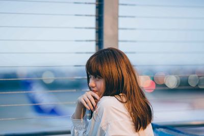 Portrait of young woman looking through window