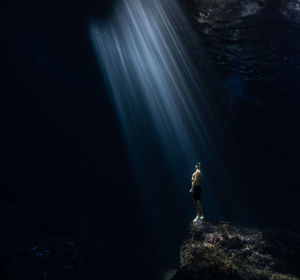 Man standing on rock with sunray underwater,