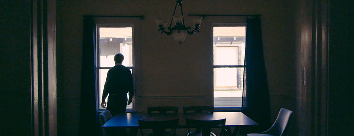 Rear view of man standing by window