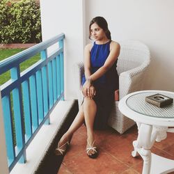 Young woman sitting on chair in balcony