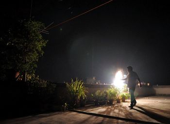 Rear view of man walking on illuminated street at night