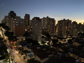 High angle view of illuminated city buildings against sky during sunset