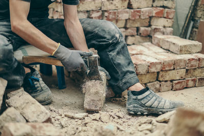 A young guy is cleaning bricks with an axe.