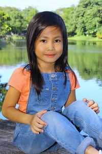 Portrait of smiling young woman sitting by lake