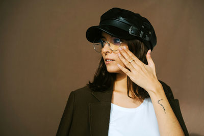 Portrait of young woman looking away against wall