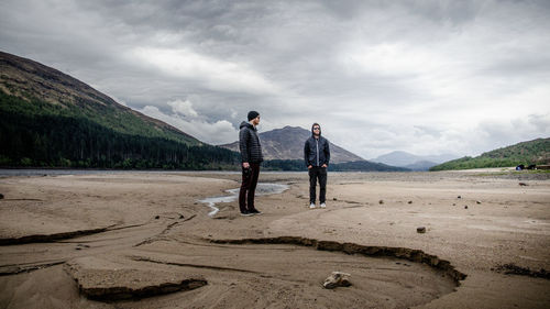 People standing on sand against sky