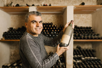 Portrait of man standing by bottles