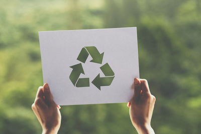 Close-up of hand holding paper against blurred background