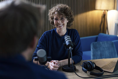 Happy presenter interviewing guest in recording studio