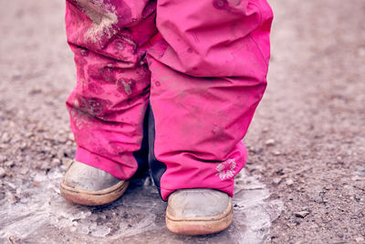 Low section of man standing on pink shoes