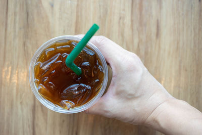 Close-up of hand holding drink on table