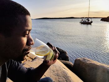 Young man having drink while sitting at beach