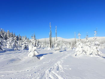 Snow covered land against clear blue sky