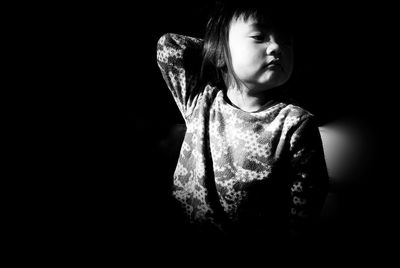 Cute smiling girl looking down against black background