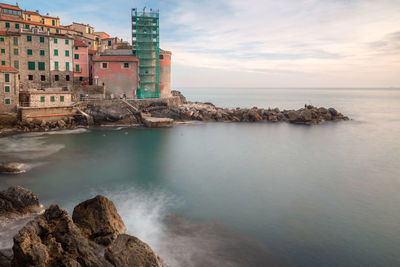 Scenic view of sea by buildings against sky