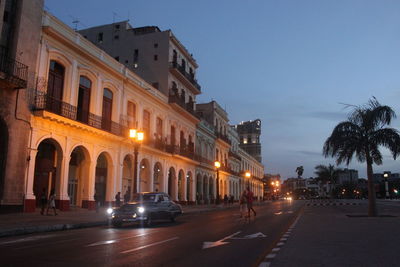 Cars on road amidst buildings in city against sky