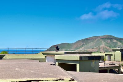 Man on roof against blue sky