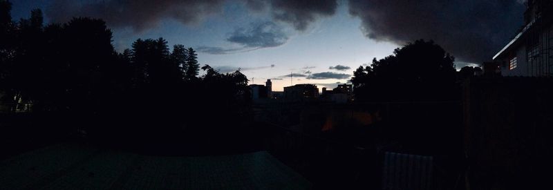 Silhouette trees and buildings against sky at sunset