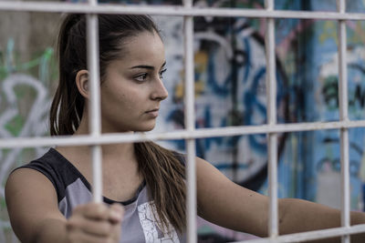 Close-up of thoughtful teenage girl seen through fence