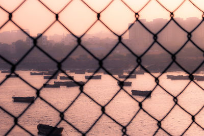 Full frame shot of chainlink fence against sky during sunset