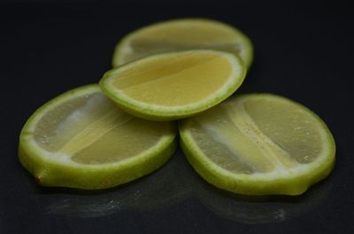 Close-up of green lemon on table against black background