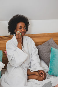 Young woman using mobile phone while lying on bed at home