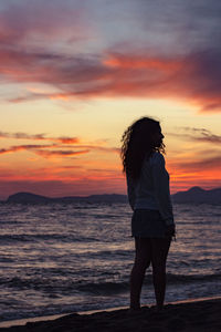 Full length of woman standing on beach during sunset