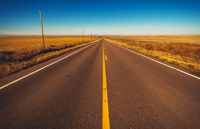 Road amidst landscape against clear sky during sunset