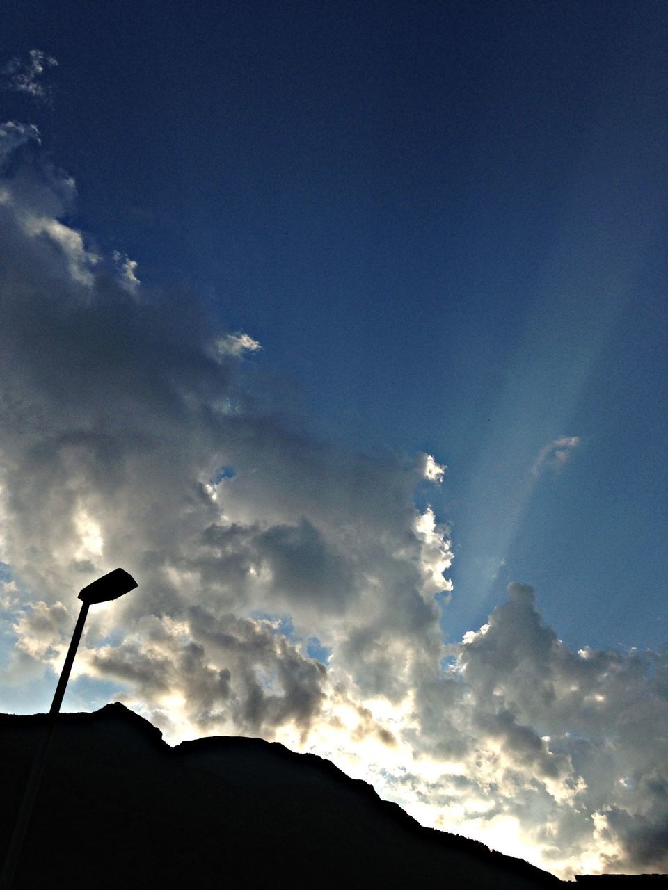 sky, low angle view, silhouette, street light, cloud - sky, beauty in nature, scenics, tranquility, nature, cloud, blue, tranquil scene, lighting equipment, sunset, dusk, mountain, outdoors, cloudy, no people, pole