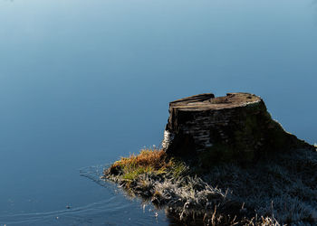 Rock formation by sea against clear blue sky