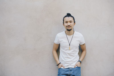 Portrait of smiling young man standing against wall