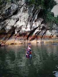 Rear view of woman standing on rock by water