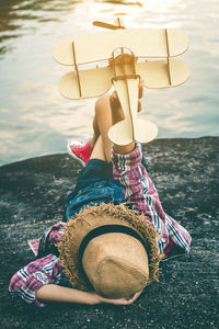 Woman with toy airplane lying down at lake