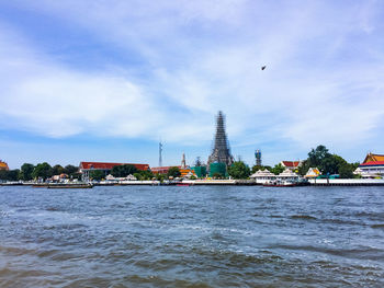 View of buildings by river against cloudy sky