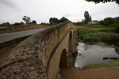 Arch bridge over river against sky