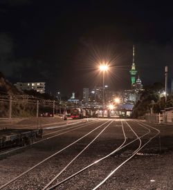 Illuminated railroad tracks by buildings in city at night