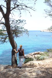 Woman standing by sea against sky