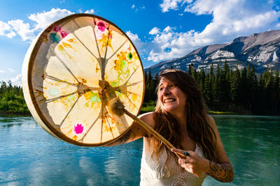 Portrait of smiling young woman in water against sky