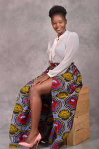 Portrait of smiling woman sitting against wall